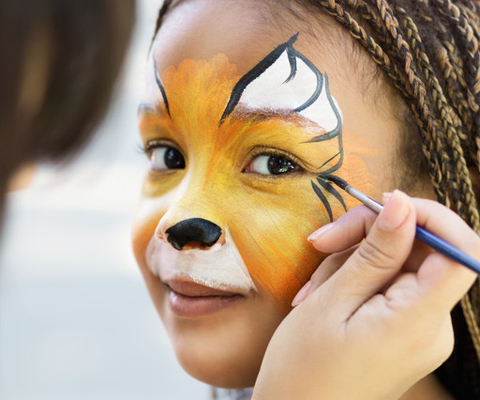 En ung flicka får sitt ansikte målat.