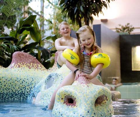 En liten flicka sitter på en flottör i en pool.