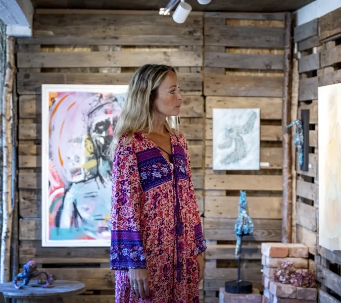 En kvinna står framför en trävägg.