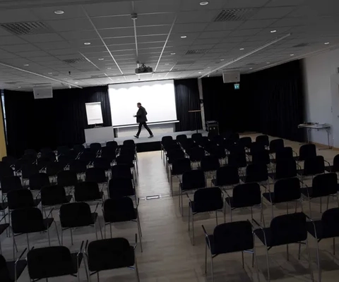 En man som går genom ett rum fyllt med svarta stolar.