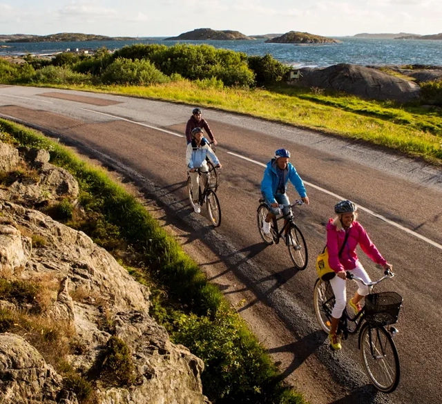 Tre cyklister längs med havskanten