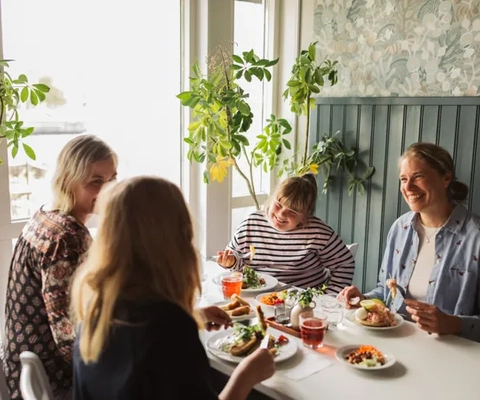 En grupp människor som sitter vid ett bord och äter mat.