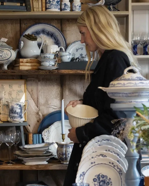 En kvinna står framför ett bord fyllt med porslin.