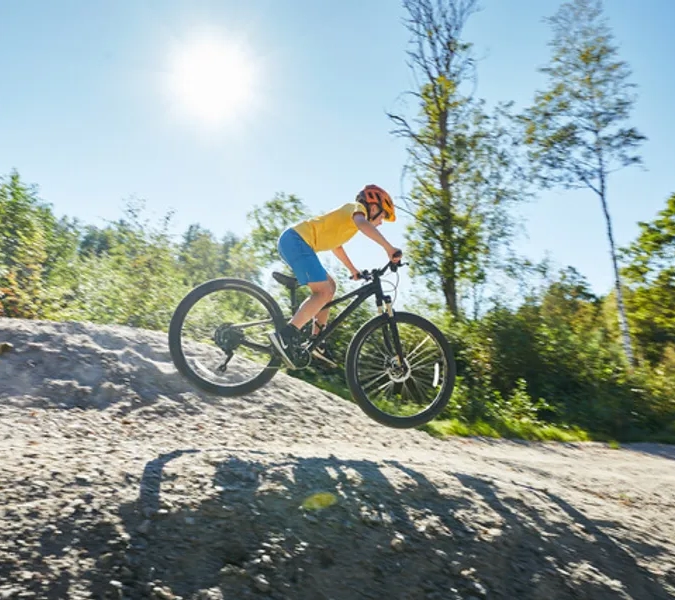 En pojke cyklar på en grusväg.