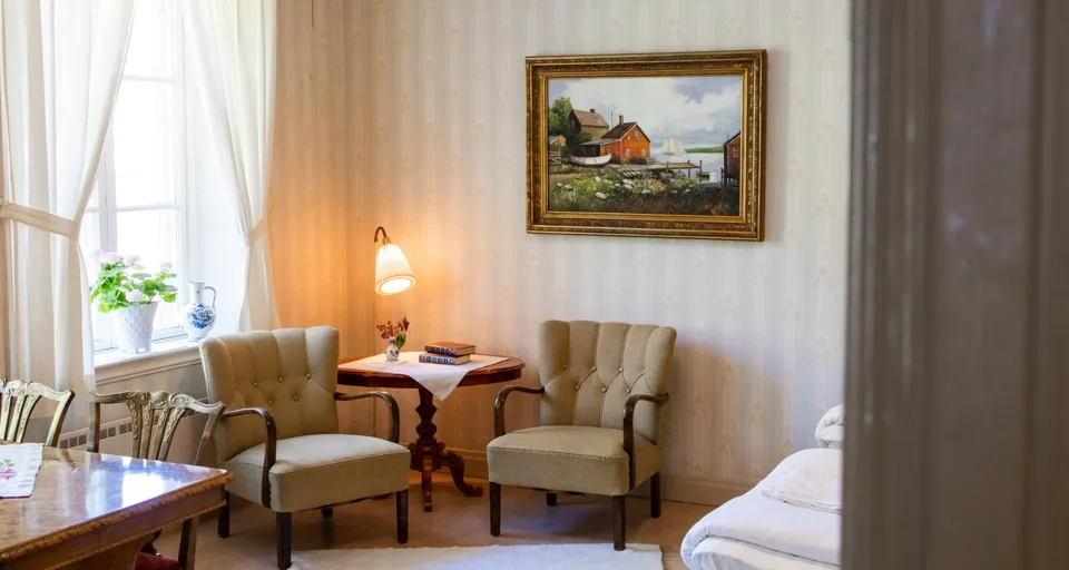 Ett rum med två fåtöljer i äldre modell. 