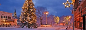 En snötäckt gata med en upplyst julgran.