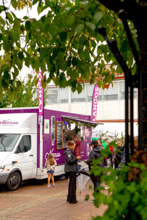 En grupp människor som står runt en food truck.