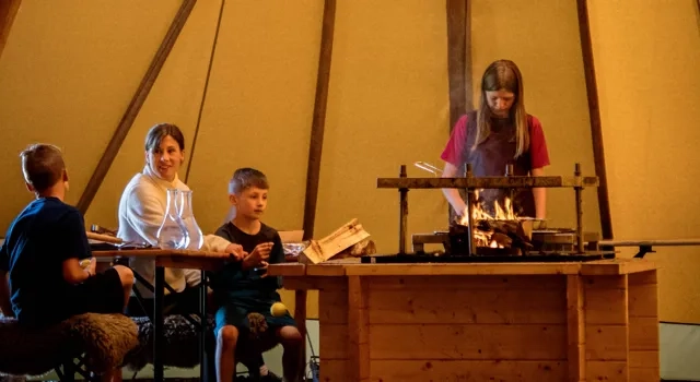 Familj umgås i ett upplyst tält.