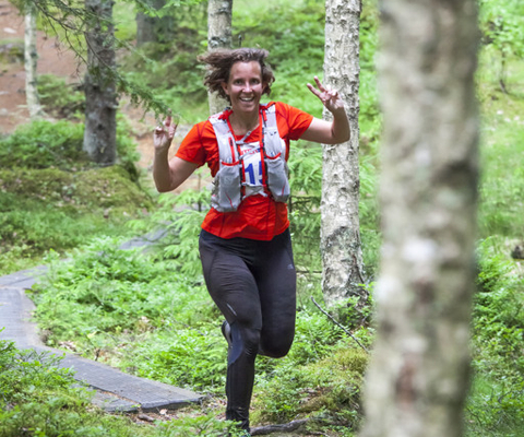 En kvinna springer genom en skog på en stig.