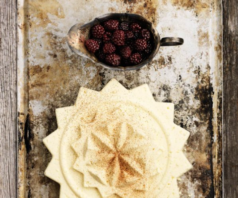 En skål med hallon som står på ett träbord.