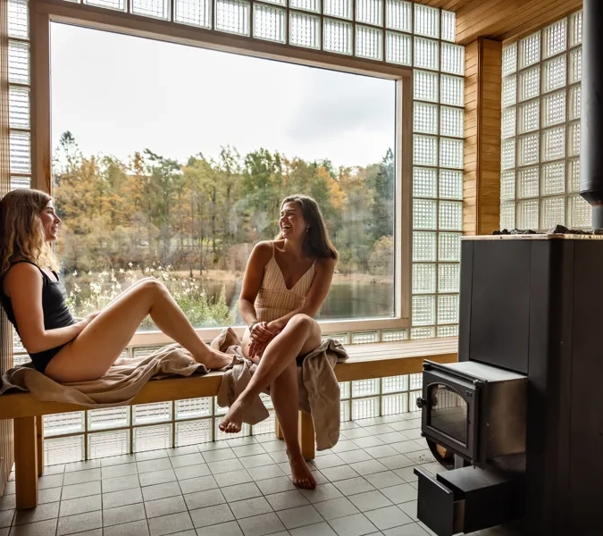 Two women sitting on a bench in front of a window.