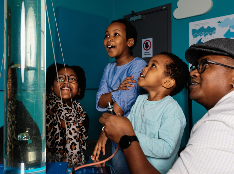 En grupp människor som står bredvid varandra och tittar på ett rör fyllt med vatten.