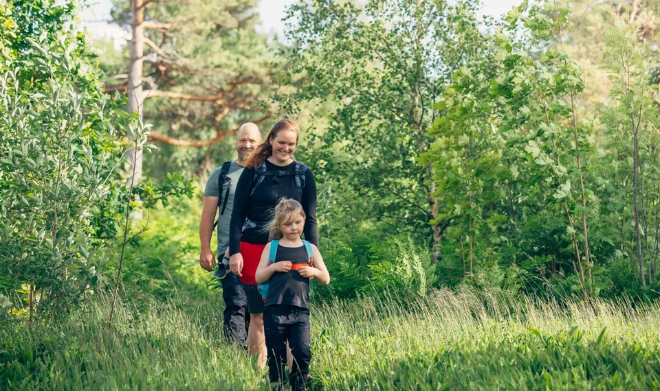 En kvinna och ett barn går genom en skog.