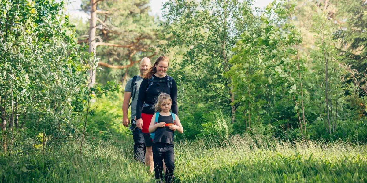 En kvinna och ett barn går genom en skog.