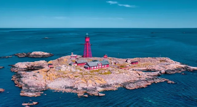 drönarfoto av ö med röd fyr och röda byggnader omringad av hav och himmel