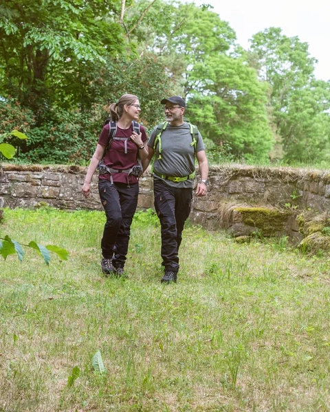 Ett par som vandrar. En stenmur syns i bakgrunden.