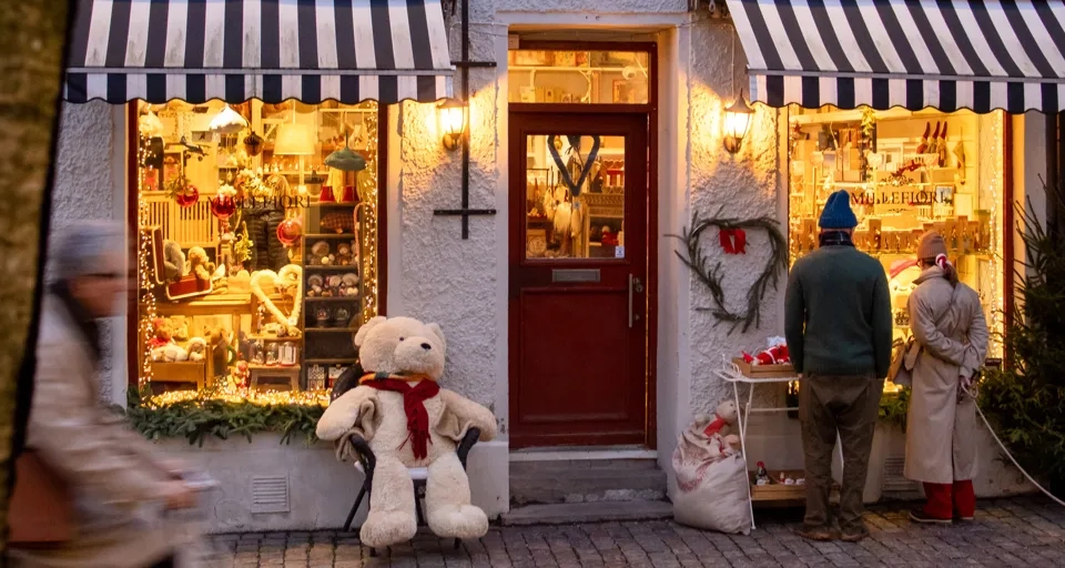 En man cyklar förbi en leksaksaffär i Haga där två personer står och tittar i skyltfönstret