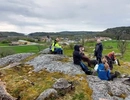 En grupp människor som sitter på toppen av en frodig, grön sluttning.
