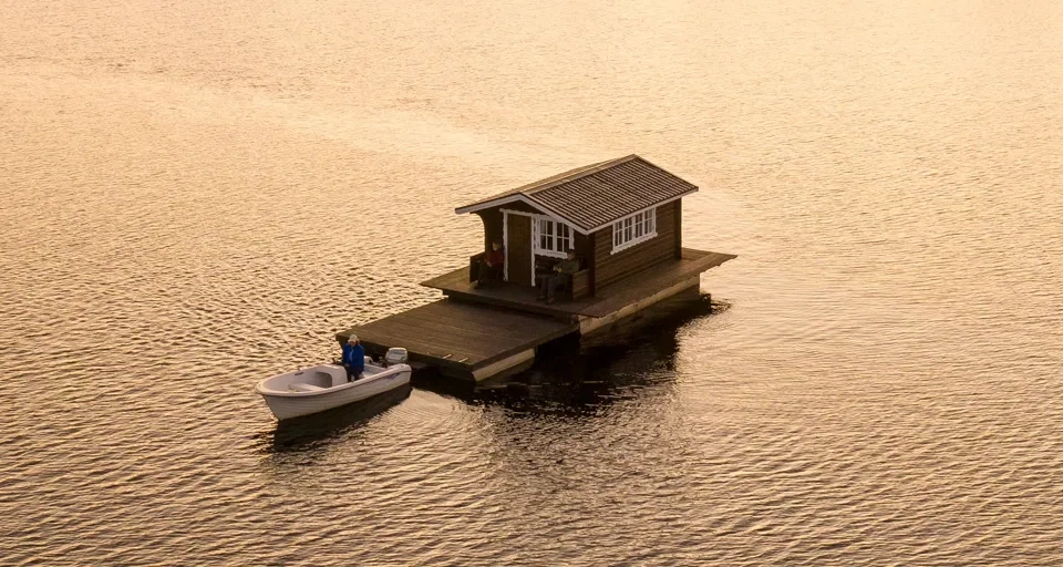 Ett litet hus som står på en pir bredvid en båt.