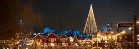 A christmas tree is lit up in the middle of a town.