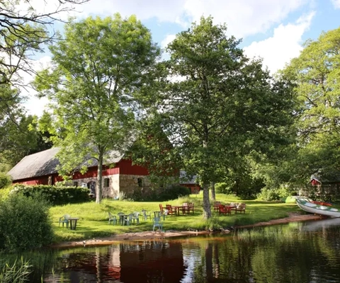 En sjö med en båt och ett hus i bakgrunden.