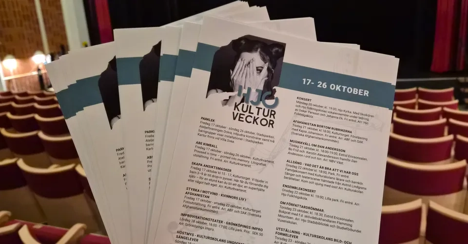En person som håller upp programblad för Hjo Kulturveckor.