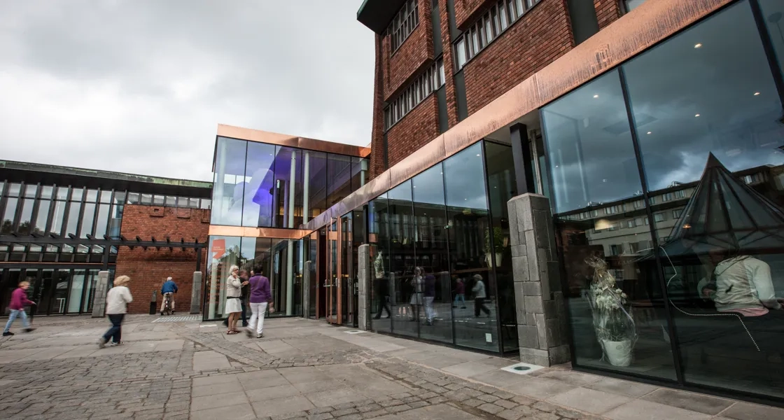 En grupp människor som går förbi en hög tegelbyggnad.