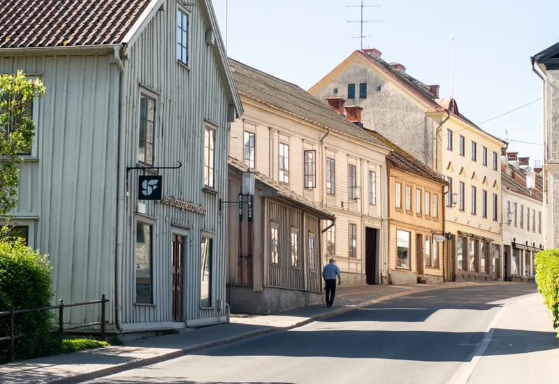 En tom gata med en person som går, gamla hus runt omkring i trä
