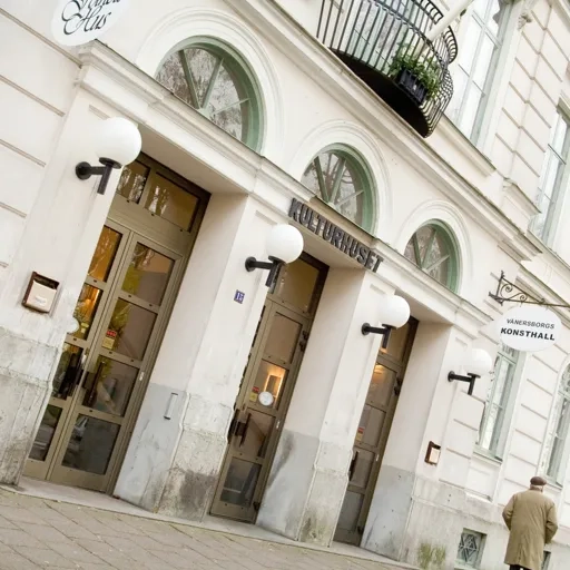 En man som går längs en gata bredvid en hög byggnad.