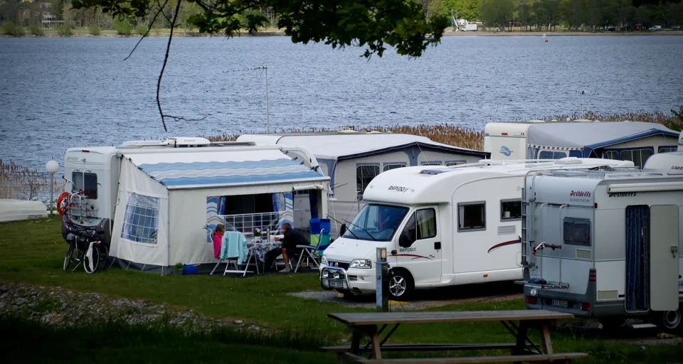 En grupp husbilar parkerade intill en sjö.