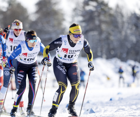 A group of people riding skis down a snow covered slope.