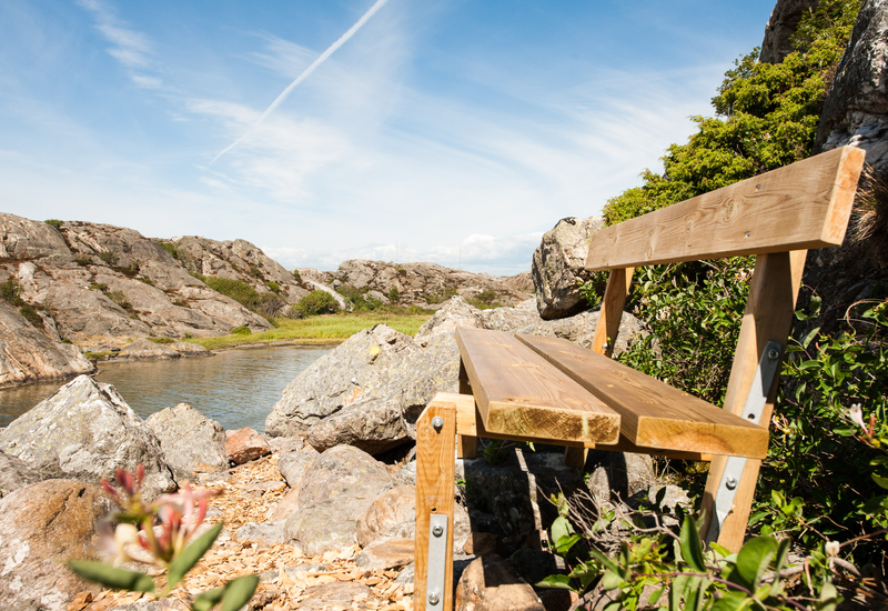 En träbänk som sitter på toppen av en stenig sluttning.