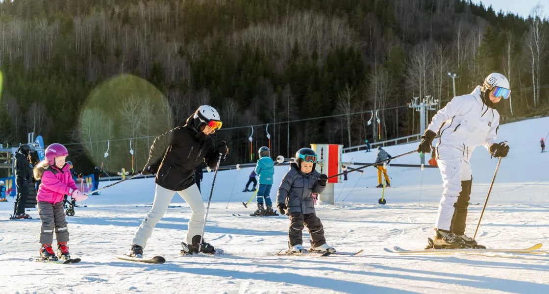 En grupp människor som åker skidor på toppen av en snötäckt sluttning.
