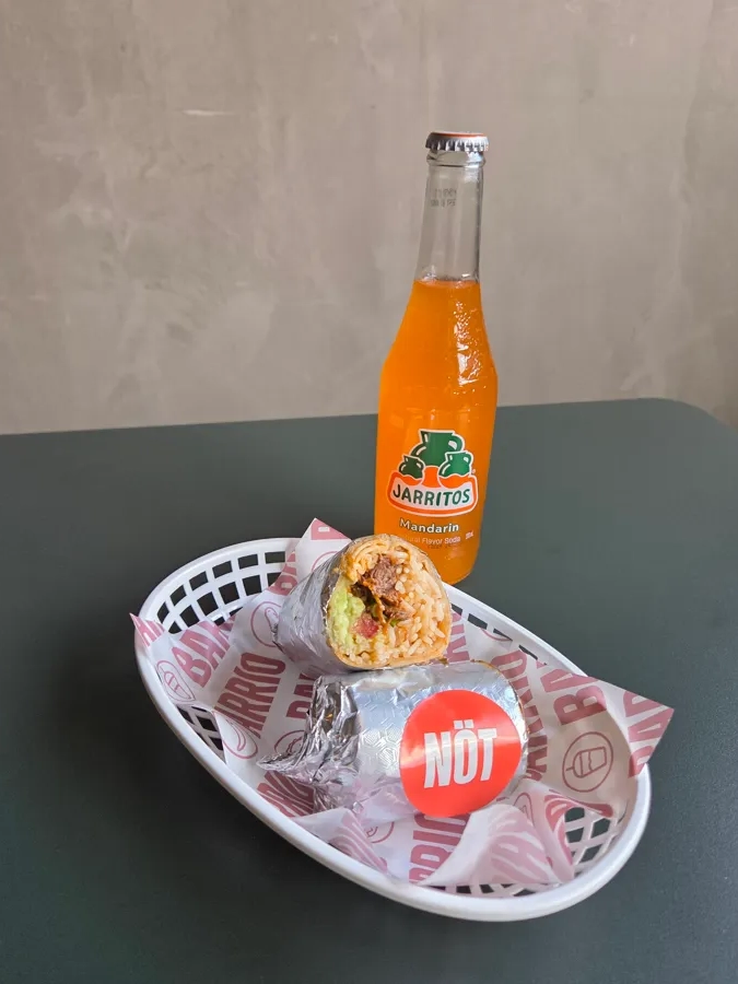 A bottle of orange juice and a sandwich on a tray.