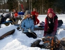 En grupp människor som sitter runt en eld i snön.
