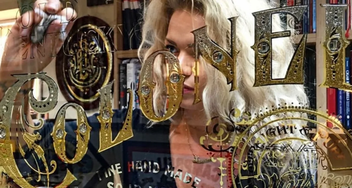 En kvinna som står och målar på en glasvägg.