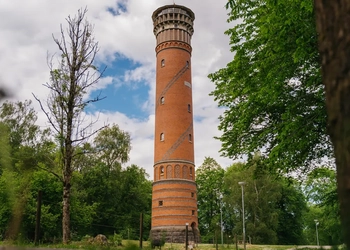 Utsiktstorn i rött tegel med träd och buskar runt omkring.