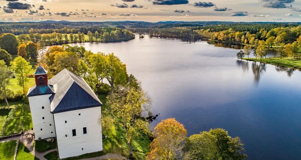 En flygbild av torpa stenhus vid en sjö.