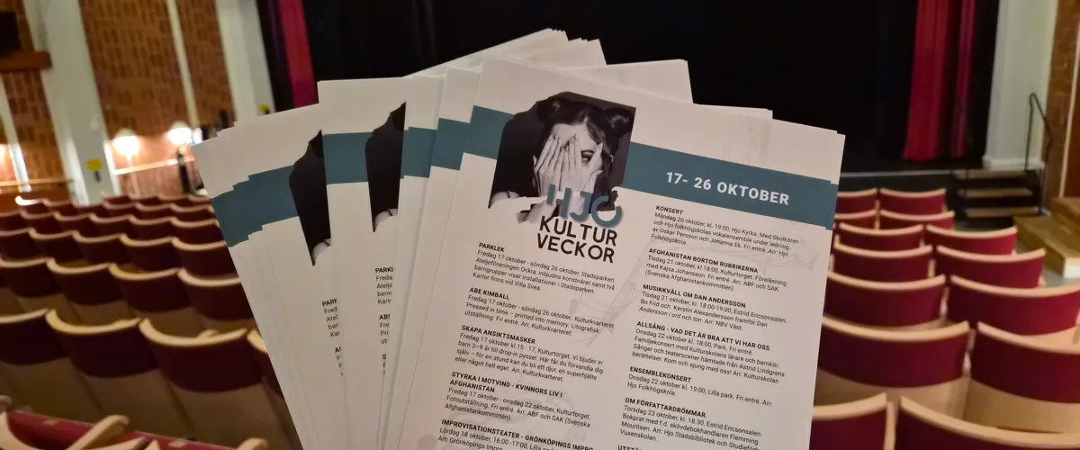 En person som håller upp programblad för Hjo Kulturveckor.