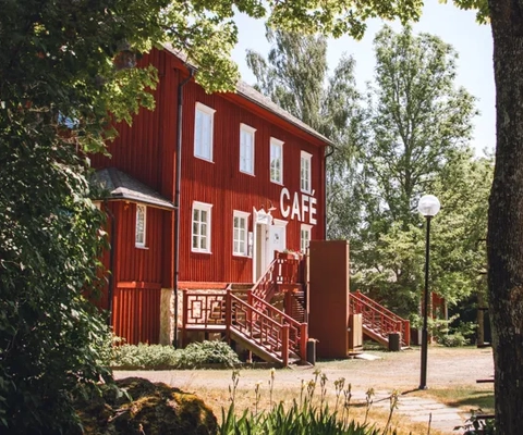 Rött hus bland gröna träd.