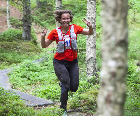 A woman running through a forest on a trail.