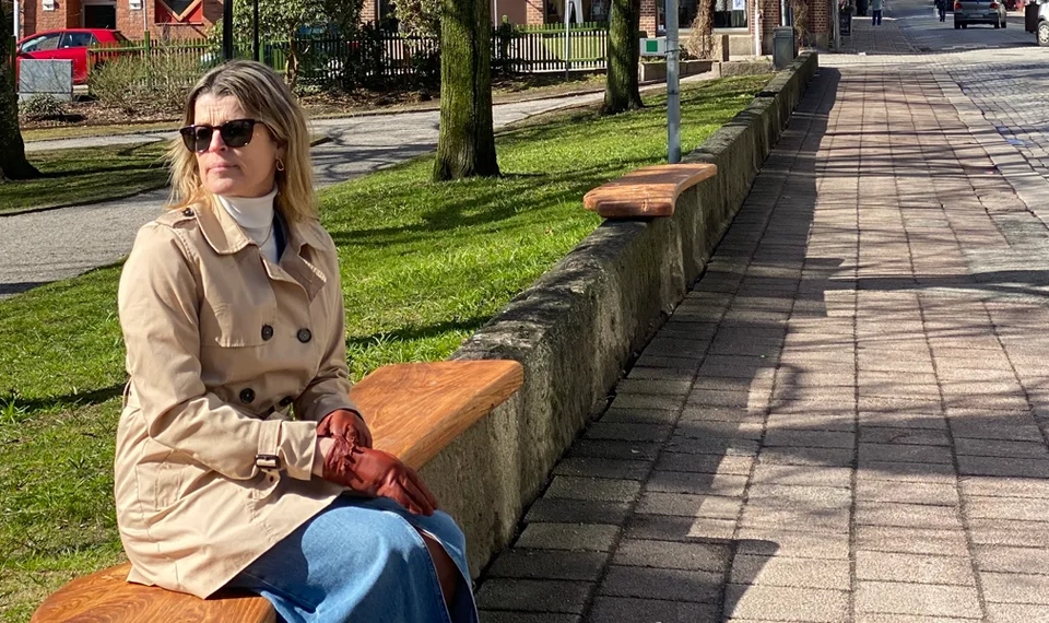 En kvinna sitter på en bänk i en park.