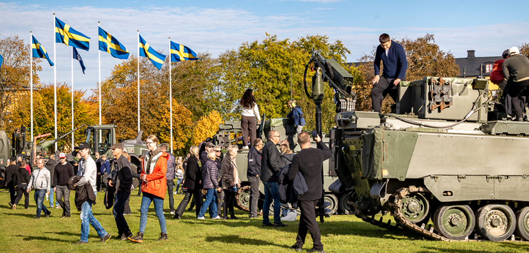 personer som tittar på militära fordon. Flaggor i baggrudnen.