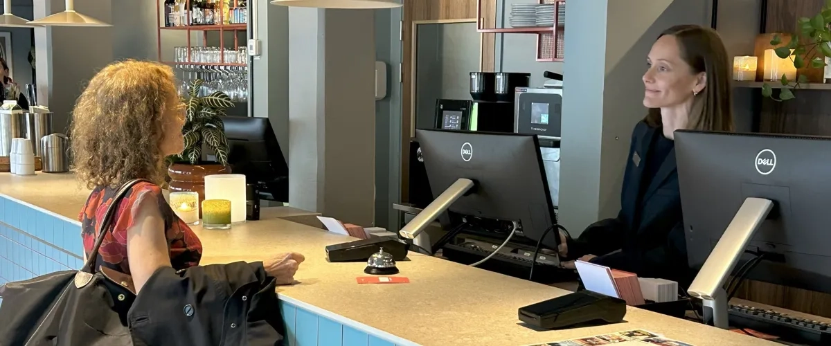 En kvinna står vid en disk och pratar med en annan kvinna.