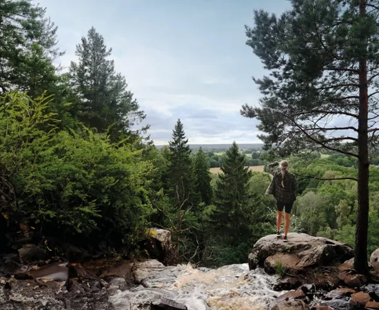 Person som står vid ett vattenfall och blickar ut över naturen