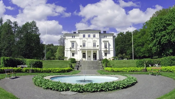 Ett stort vitt hus med en fontän framför.