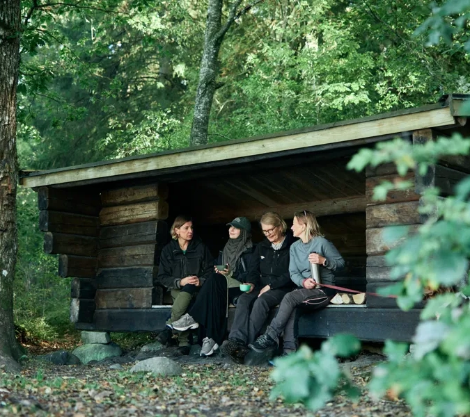En grupp människor som sitter på en bänk i skogen.