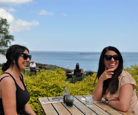 två tjejer sitter vid bord och ler