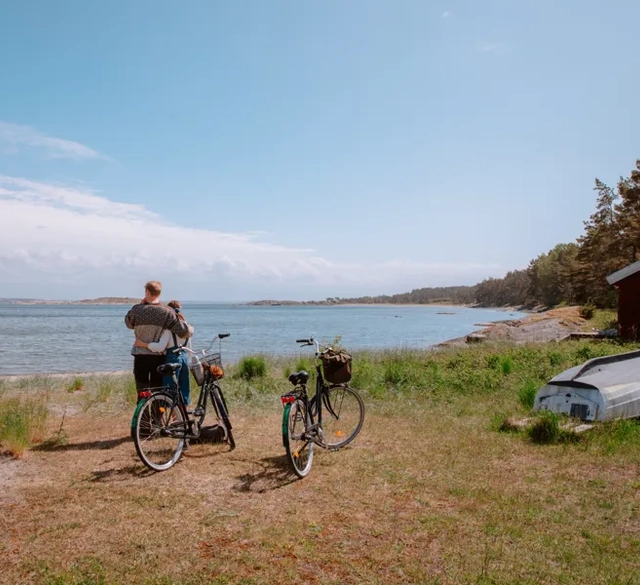 En man och en kvinna som står bredvid sina cyklar vid en strand på Sydkoster