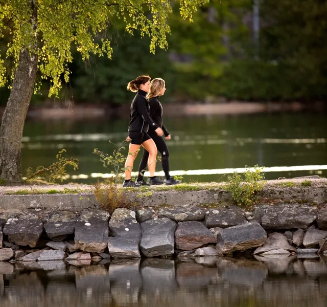 Två personer som promenerar längs vattnet